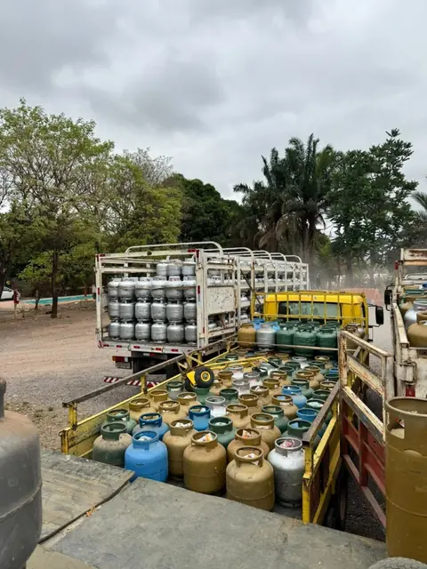 Caminhões com botijões de várias cores no pátio do depósito