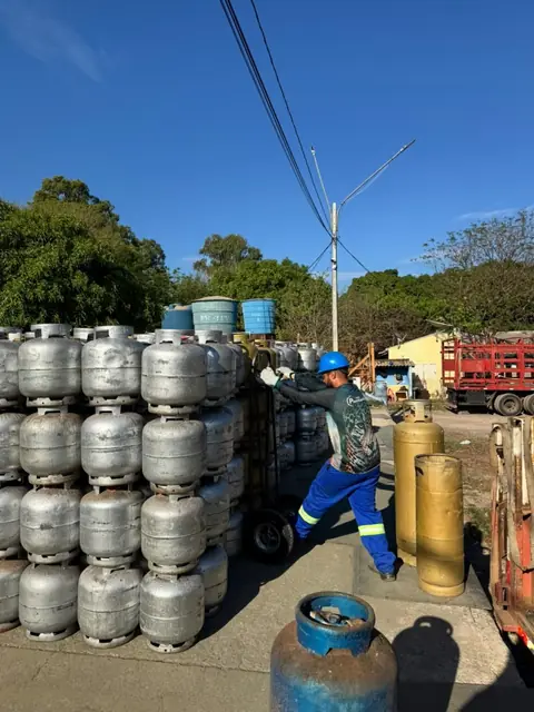 Colaborador movimentando botijões ao lado das pilhas do estoque