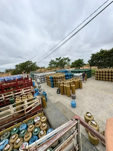 Vista do pátio do depósito com pilhas de botijões e caminhões sendo carregados