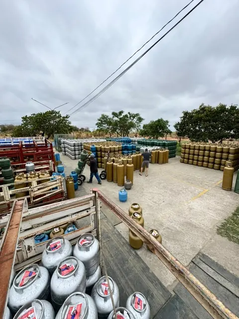 Colaboradores movimentando botijões no pátio de concreto do depósito